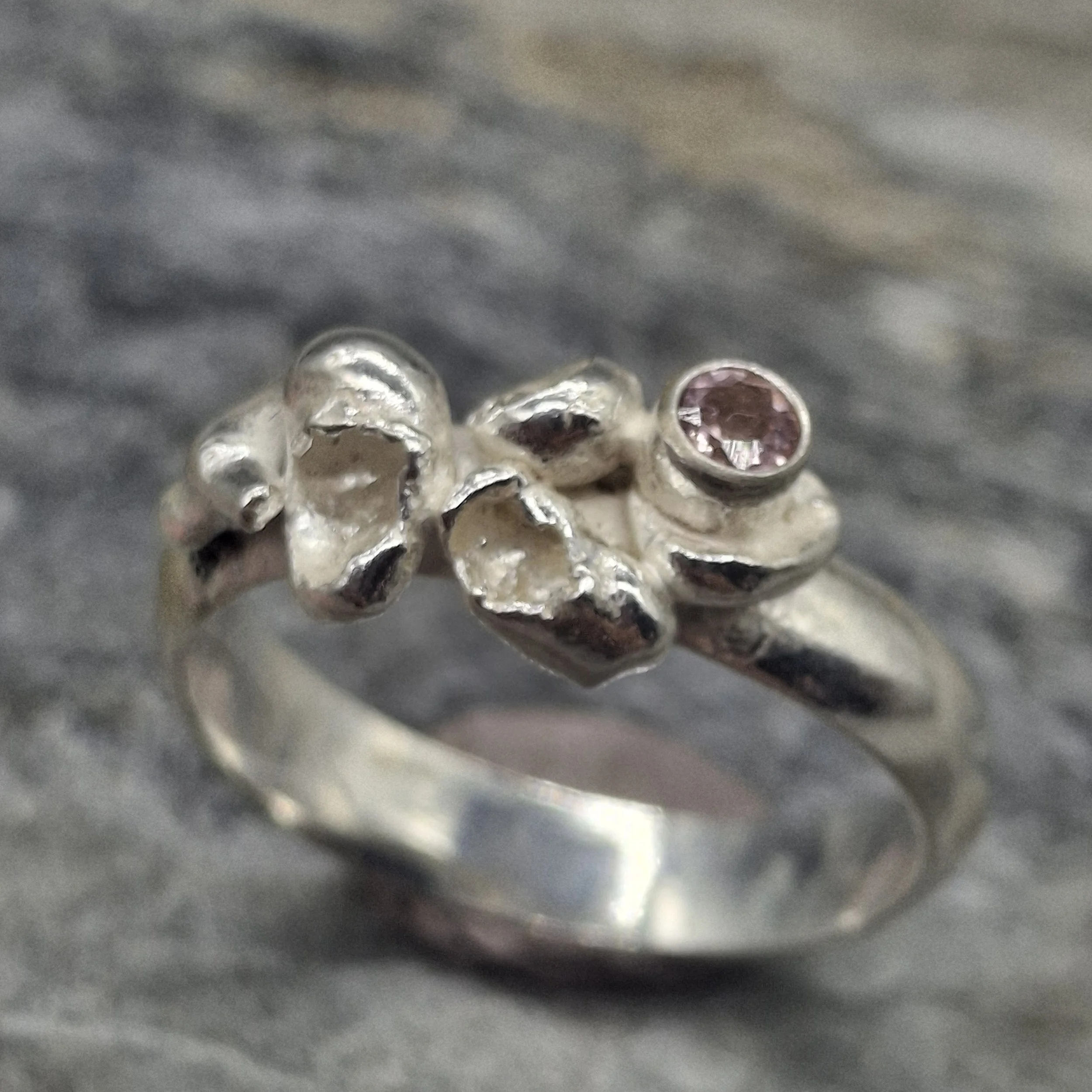 Handmade sterling silver Fallen Blossom ring with water-cast petal textures, featuring a pale pink tourmaline nestled in organic silver.