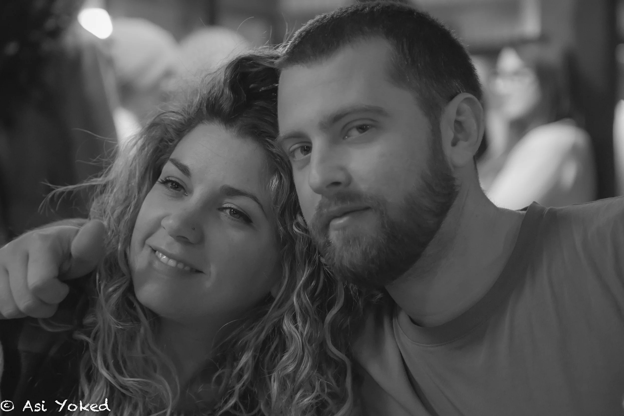 Black and white photo of a woman and man taking a selfie together, smiling, with the woman's arm around the man's shoulder.