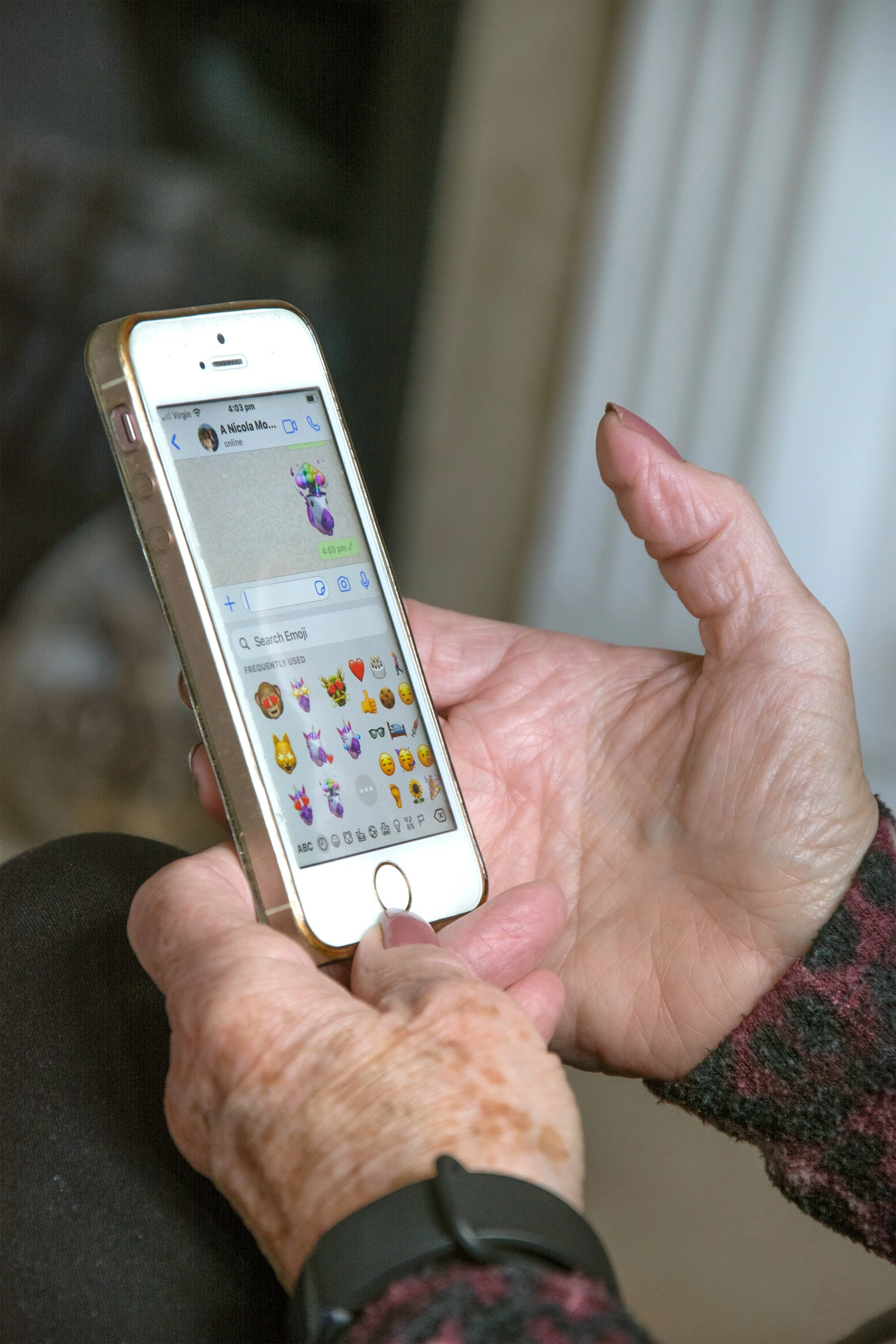A person holding a smartphone with a messaging app open, showing a sticker of a unicorn with balloons in the message window.