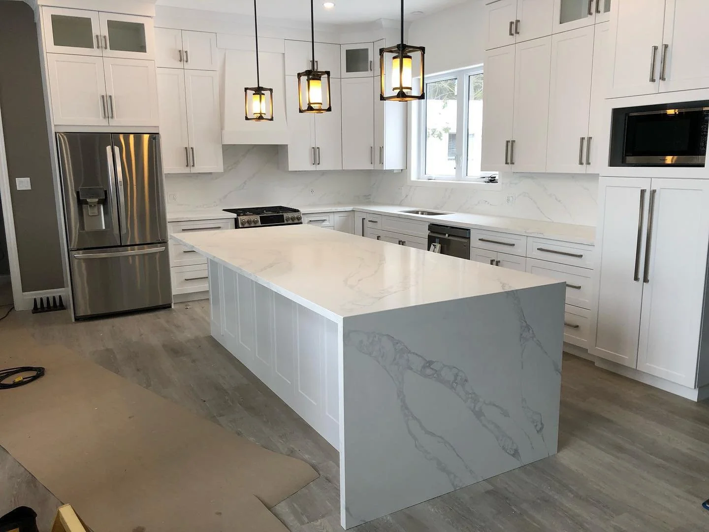 Oceana Quartz kitchen countertops with bookmatched waterfall island and full height backsplash.