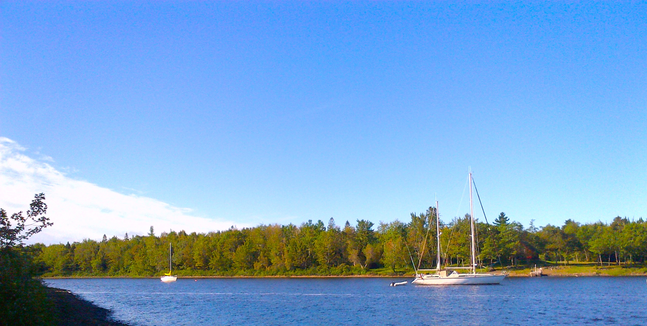 Peregrinus safely anchored in Halcyon Cove, inside Cumberland Bay, Grand Lake. The Zodiac hangs from Peregrinus' stern and Garry's Happenstance lies on a mooring deeper inside the cove. BlackBerry 9900, 7 September 2014.