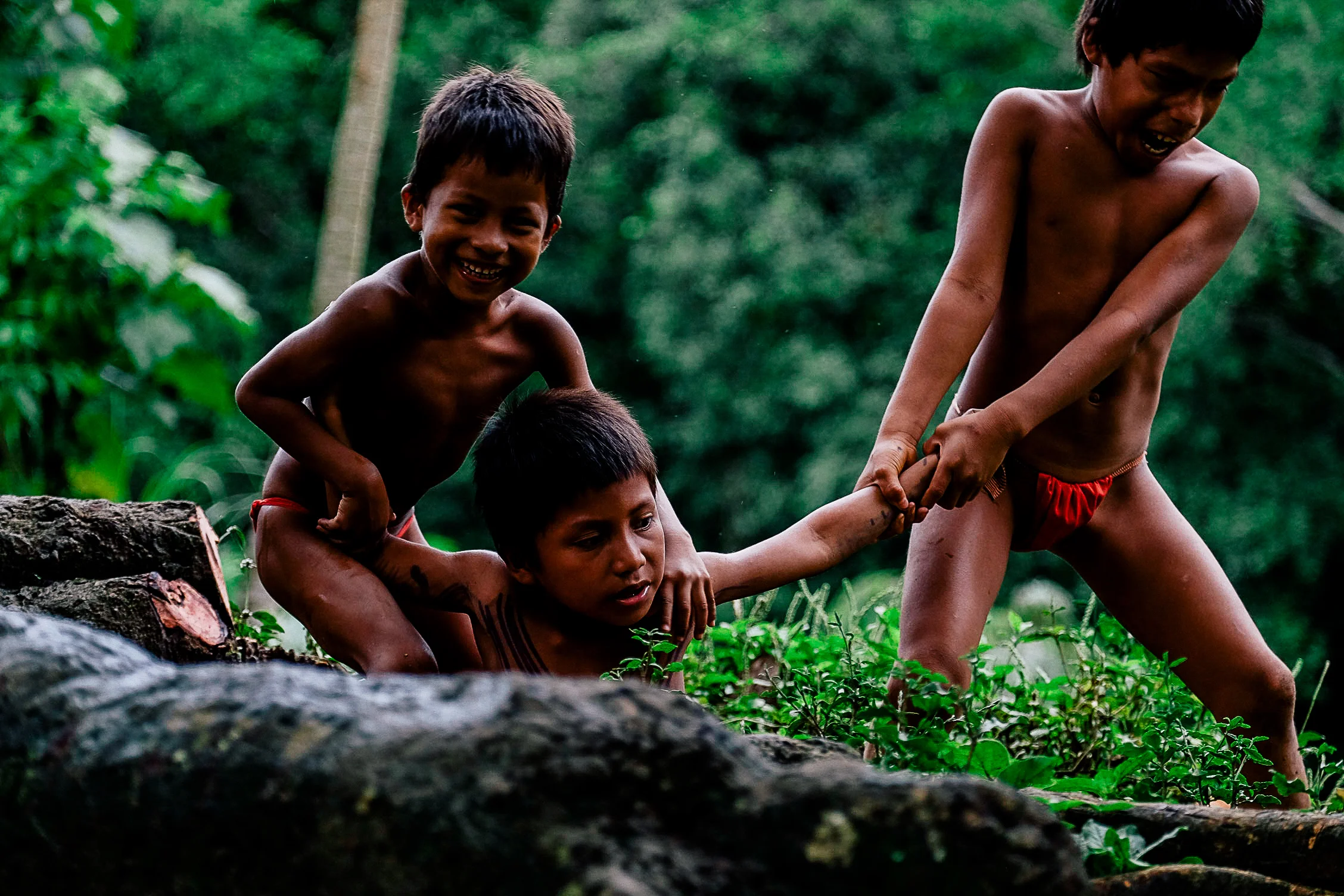 Three Embera children are play fighting by the river. It is comforting to see the children of the village finding ways to have fun without technology, play fighting, playing tag and even drawing games on the ground with rocks. This brings back nostalgic feelings from my childhood before technology really took hold of our lives.