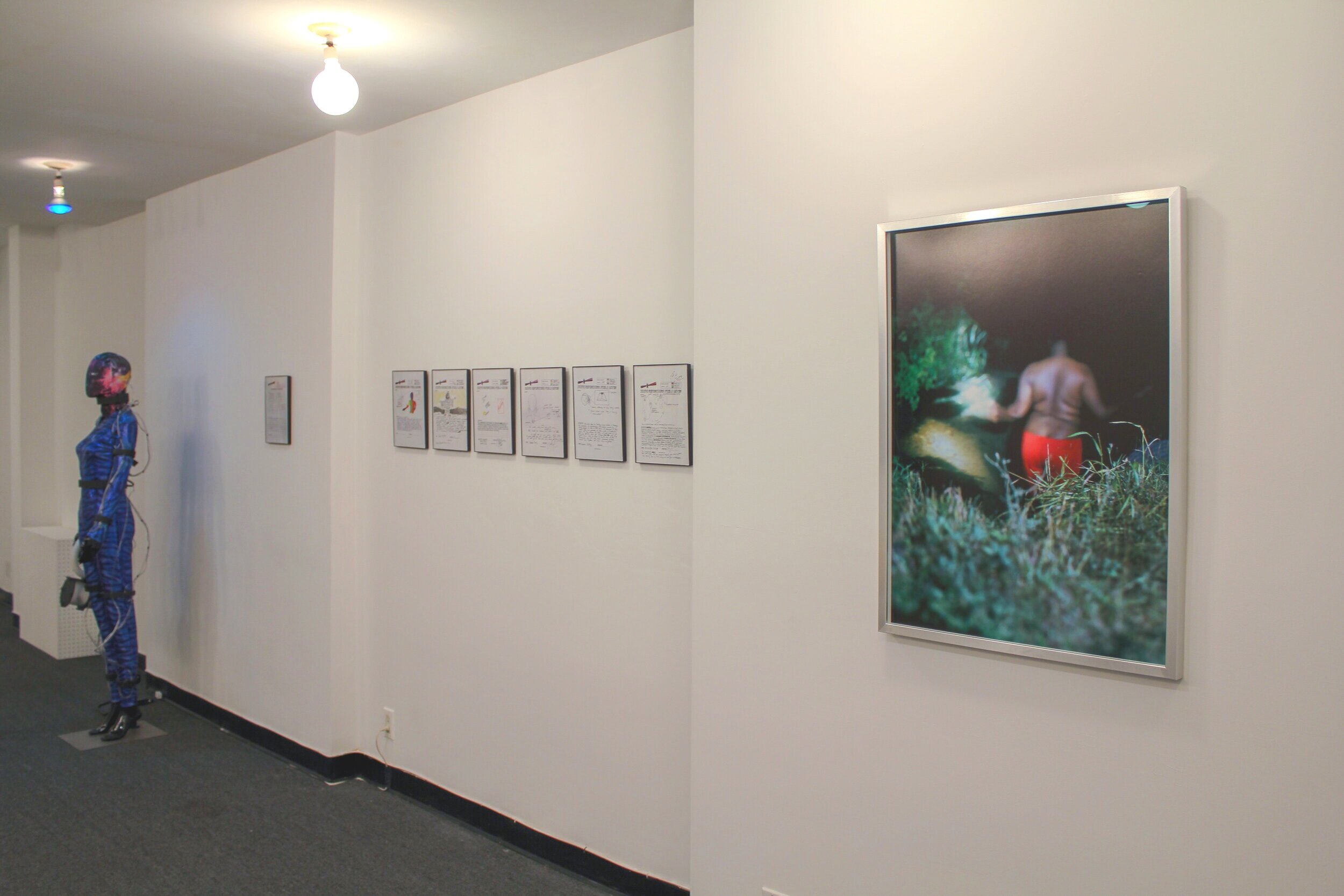  Installation View of Iyapo Repository’s    Artifact 012: Sensory Body Suit , 2016;   Manuscripts,   2016 – ongoing; Kearra Amaya Gopee’s,  darryl (looking in the water for someone who isn't you),  2017  