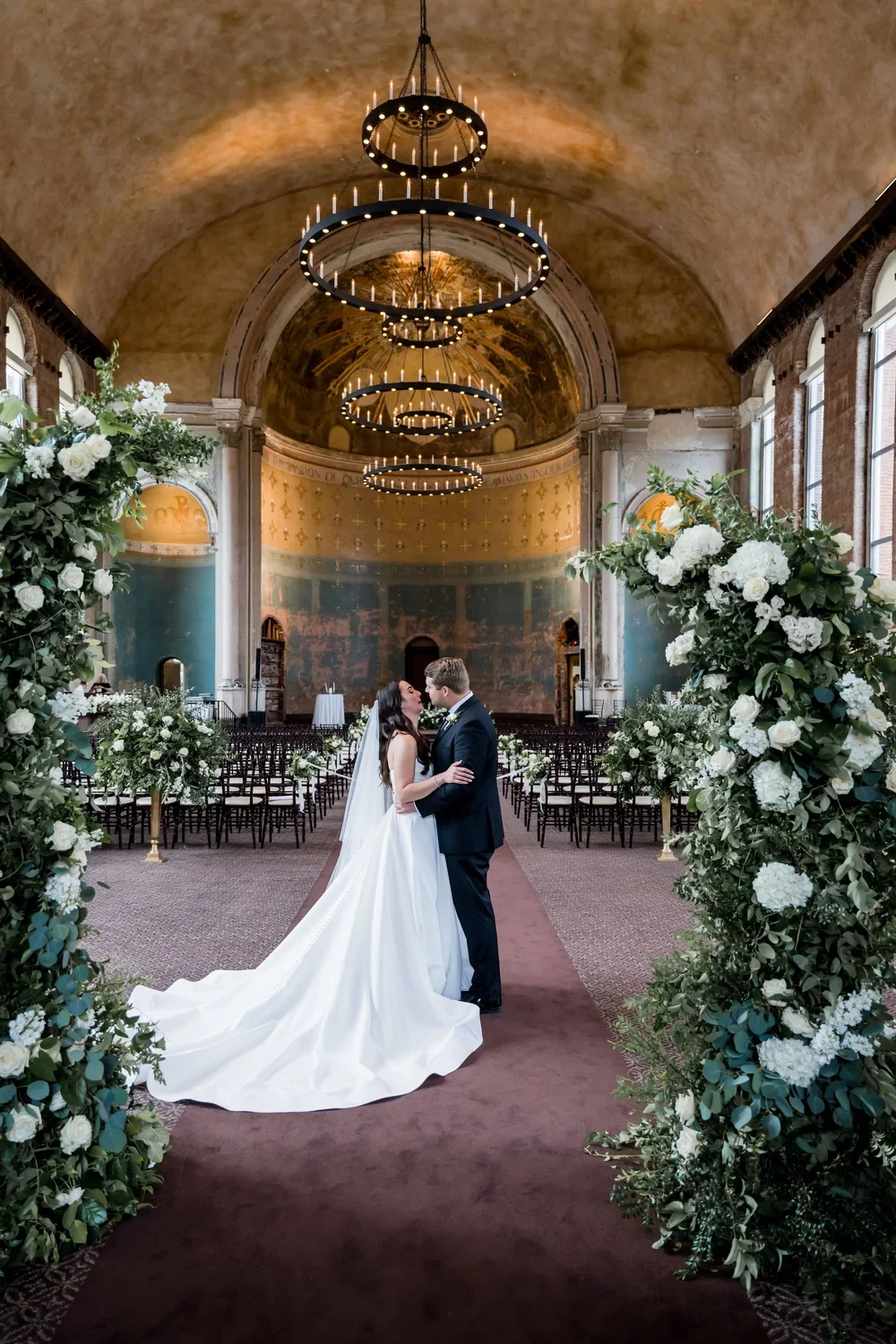 Bride and Groom Kiss Under Floral Ceremony Arch