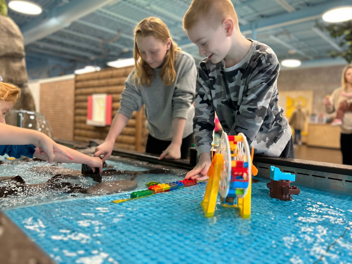 Children playing on a water table with interchangeable dam tabs