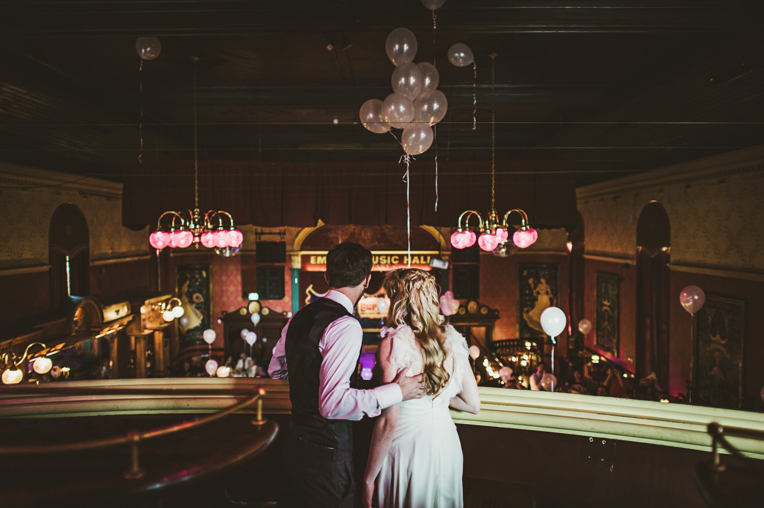 Couple on balcony watching guests at Empire Music Hall wedding.