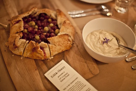 Gourmet tart on wooden cutting board with sauce in cup and 15th century feast menu.jpg