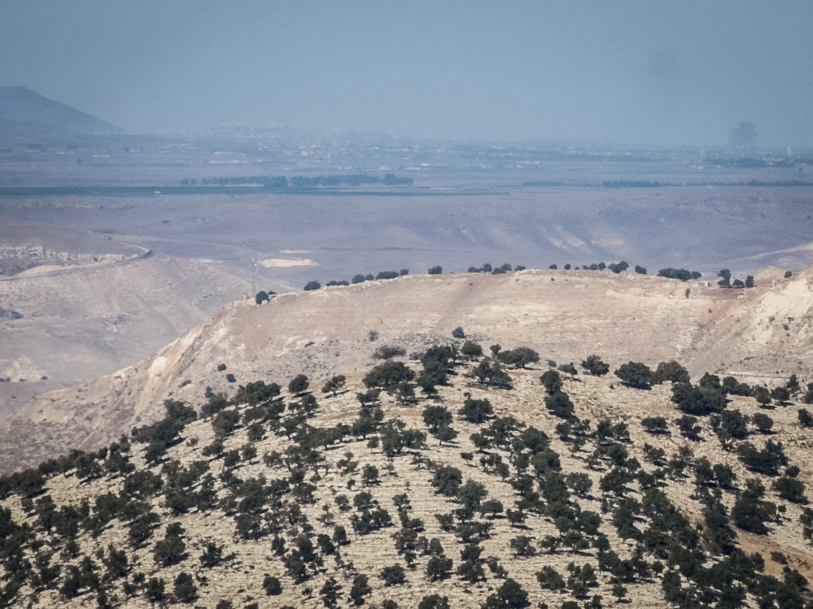 Umm Quais Jordan - While we were totally safe at this beautiful, historical location, you can see on the horizon on the right one plum of smoke from a shell a few minutes earlier, and another shell that has just hit. About 15 miles up the road from our beautiful little setting people were using artillery to kill each other. A bit surreal.