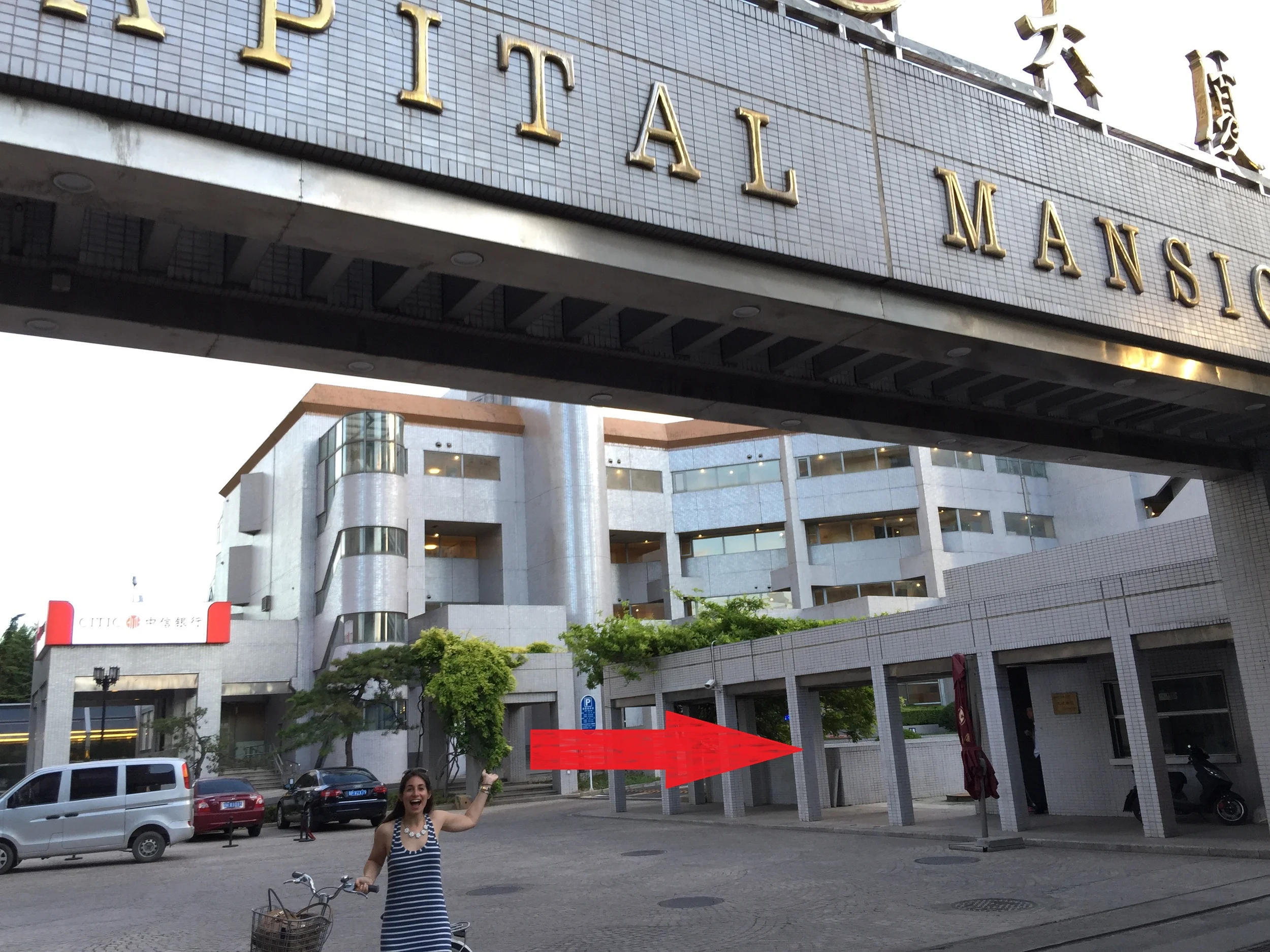 2. Soon, you'll come to a large gate that reads "CAPITAL MANSION." Turn left into this gate, and then right in the direction of the arrow, through the archways. 