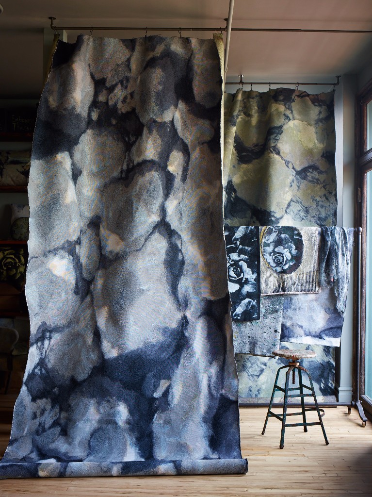 Fabric drops of our "Rock Pool" and "Ripple" jacquards frame the studio fabric rack that is filled with fabric samples, including pieces of our "Melting Rose" in Sky Blue.