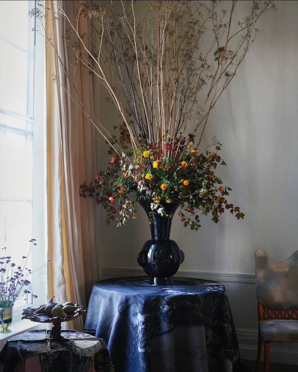 The black Penny vase from 1882Ltd in a fountain of forestry from Nikki Tibbles Wild at Heart. Jacquard textiles from MTS.