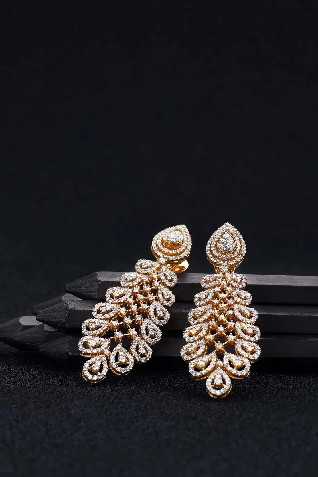 Intricate gold and diamond necklace and earrings set on black background, featuring detailed floral motifs and teardrop designs.