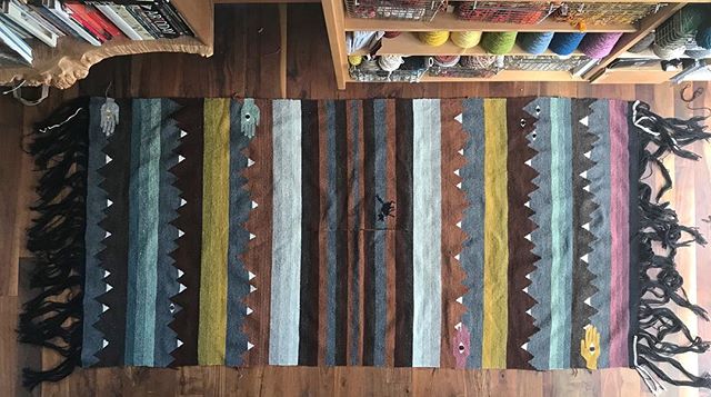 Birds eye view of the poncho I wove for my husband. From an objective point of view this thing turned out beautifully. From a practical standpoint, WTF?! It’s huge. Like, this might work for Andre the Giant or a yeti, but never in a million years for a regular sized human being. It’s so big I had to climb up a ladder to even take a photo of it. What happened? I looked at my original plan and it turns out I did actually weave it to spec. The draw-in on the weaving is about as much as I thought it would be for both length and width. One side is a few inches longer than I planned, but pulling out the purple/pink stripe would have fixed that. I have no idea why (or how?) I came up with such outsized original measurements. It’s a mystery. It’s bigger than it needs to be in every direction by almost a foot. Except for the slot in the middle, that’s right on point. The good news is that it makes an excellent blanket. It’s so big that we can both cuddle up under it on the couch without having to try and steal a little more blanket to our side in order to get cozy. You can tell by the wrinkles that it’s seen a lot of snuggling already. The other good news is that I over ordered the yarn I used to weave it so I should have enough to make another poncho, especially since the next one will be about 25% smaller. And hopefully 25% faster.