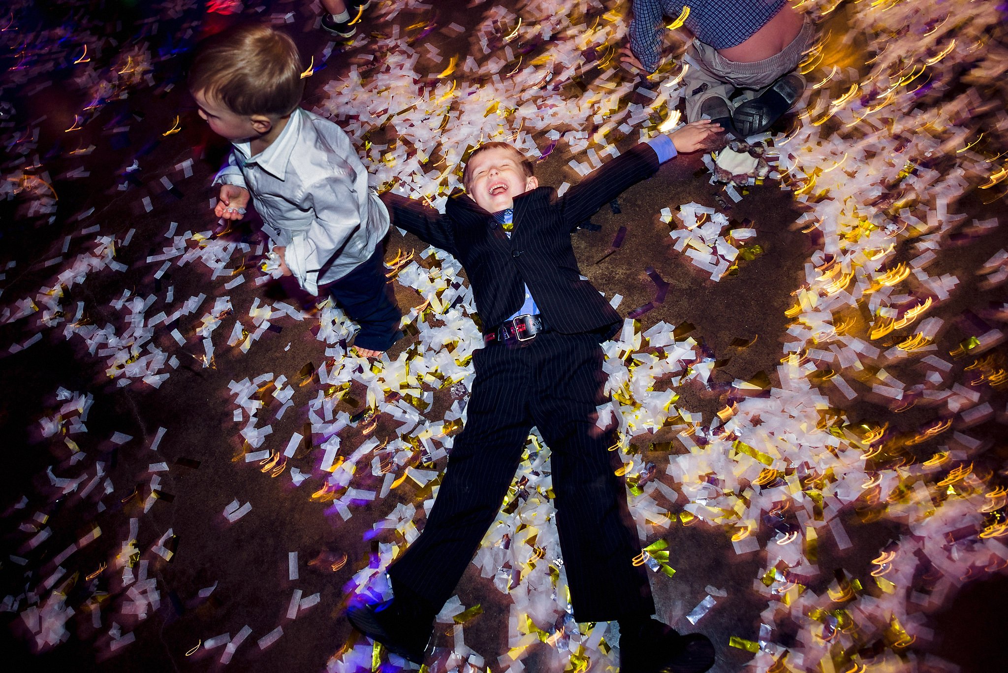 Kids making snow angels in the confetti on the dance floor in wedding reception at Pecan Ranch in Dripping Springs, Austin, Texas