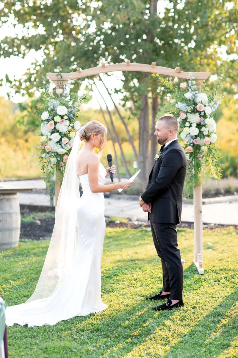 bride reading vows to groom during their outdoor wedding ceremony