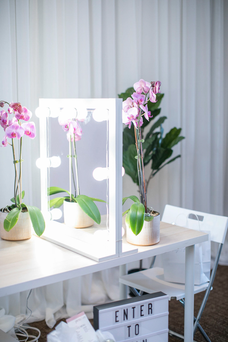 bridal hair and makeup booth with orchids and lights