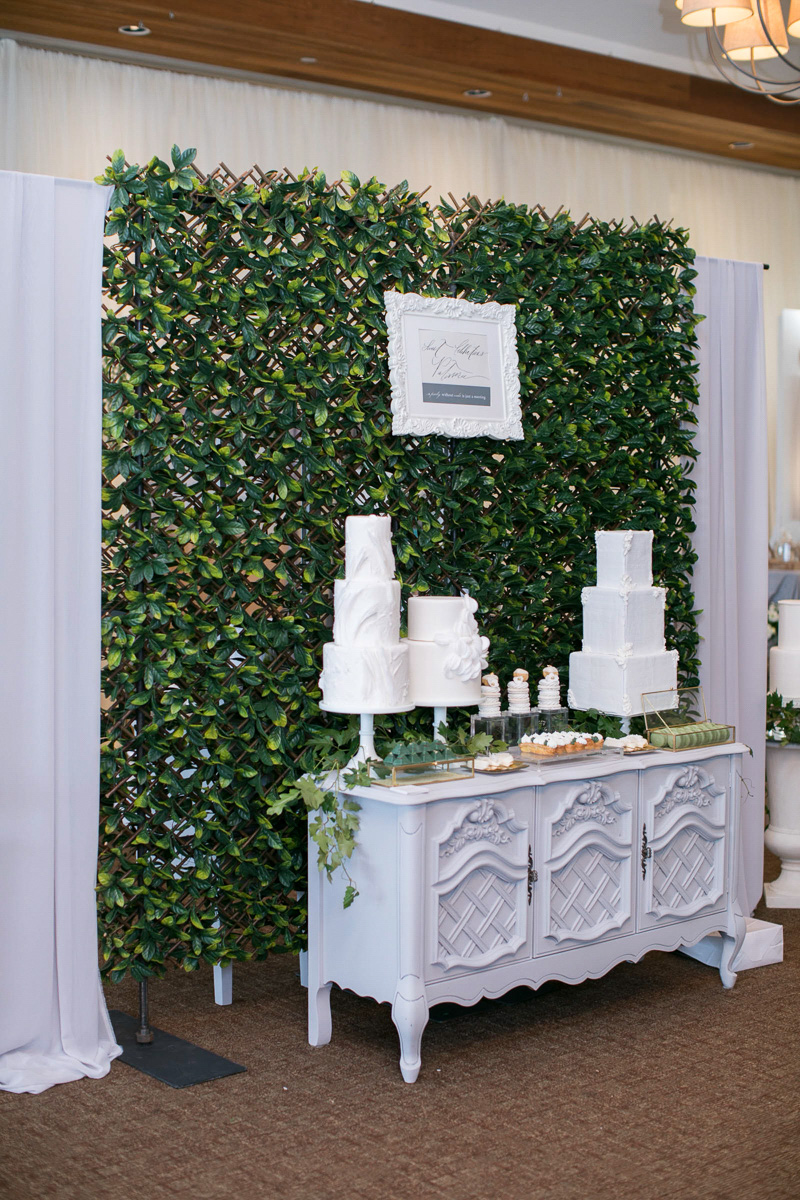 wedding day cake and sweets table display with greenery backdrop