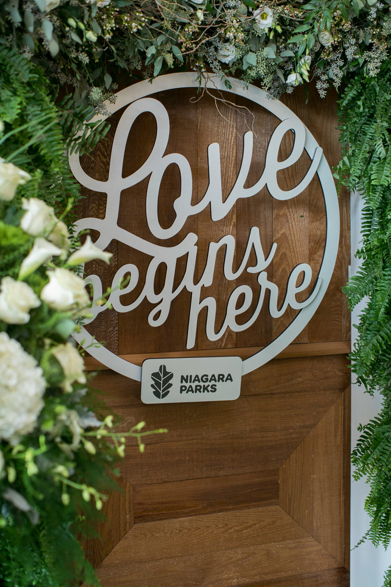 closeup image of love begins here wood hanging sign