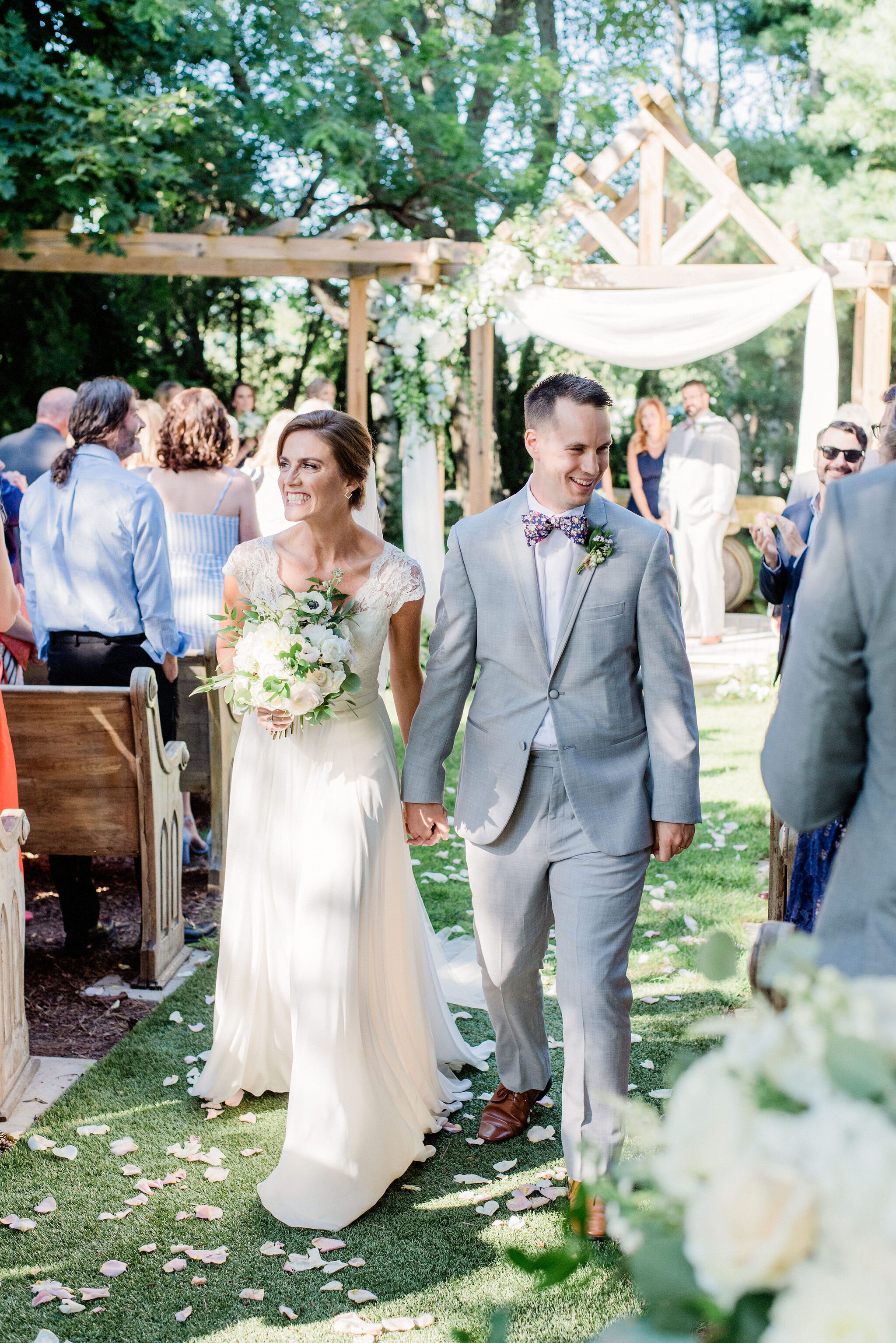 bride and groom walking down the aisle of outdoor winery wedding ceremony smiling hand in hand just married