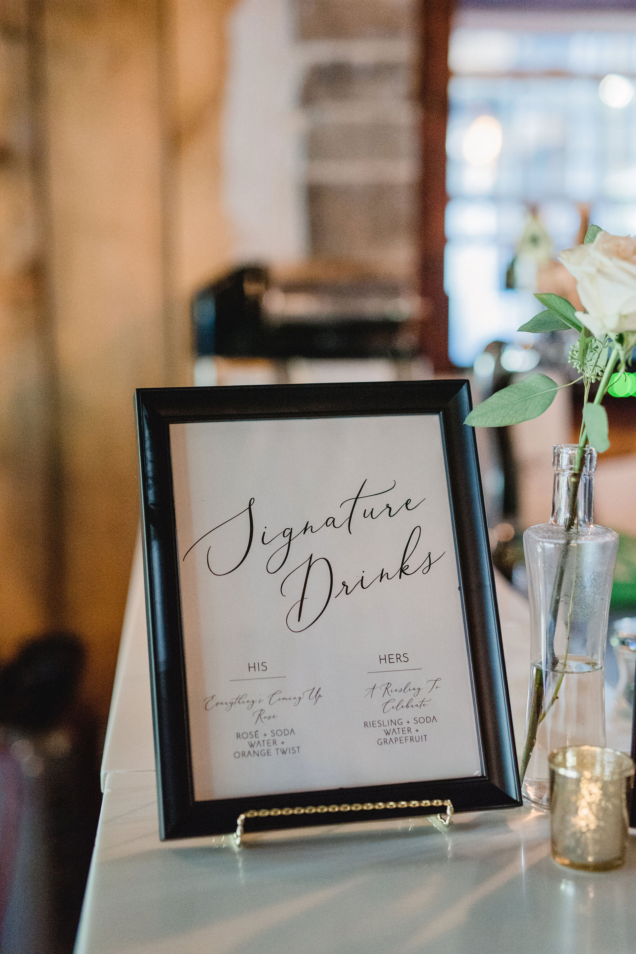 signature drink black framed sign sitting on top of the bar at wedding reception