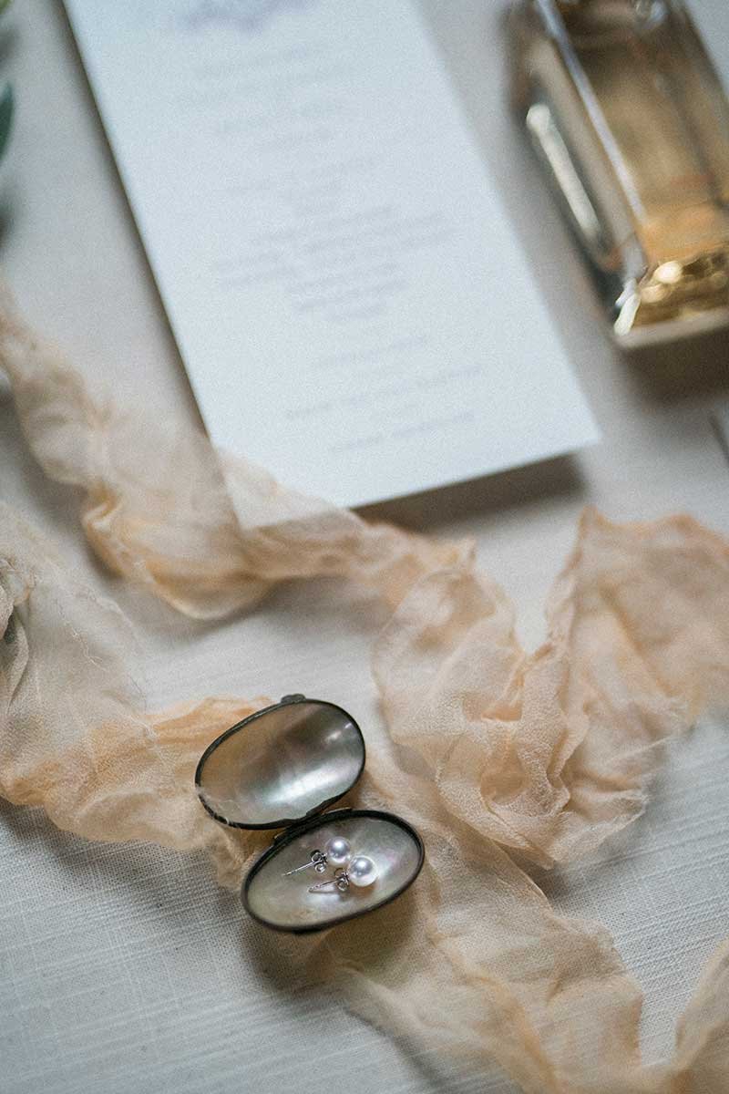  Flatlay of wedding details including invitation and jewellery. 