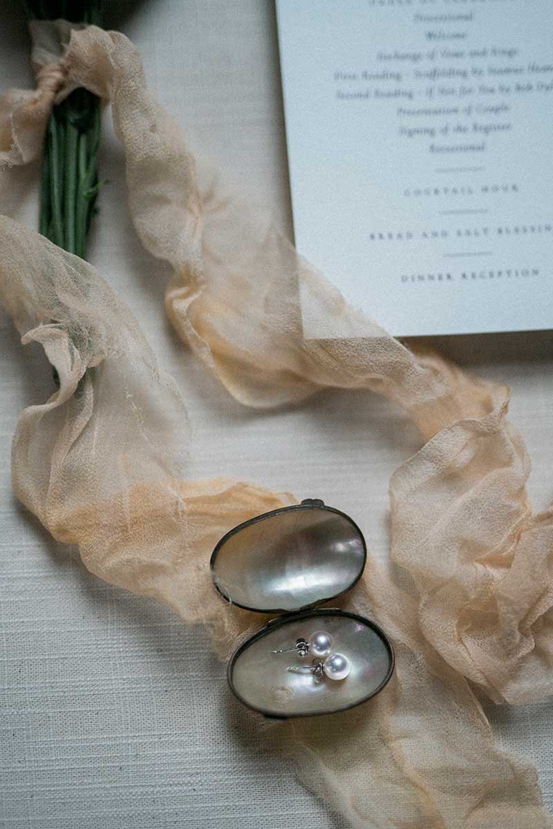  Flatlay of wedding details including invitation and jewellery. 