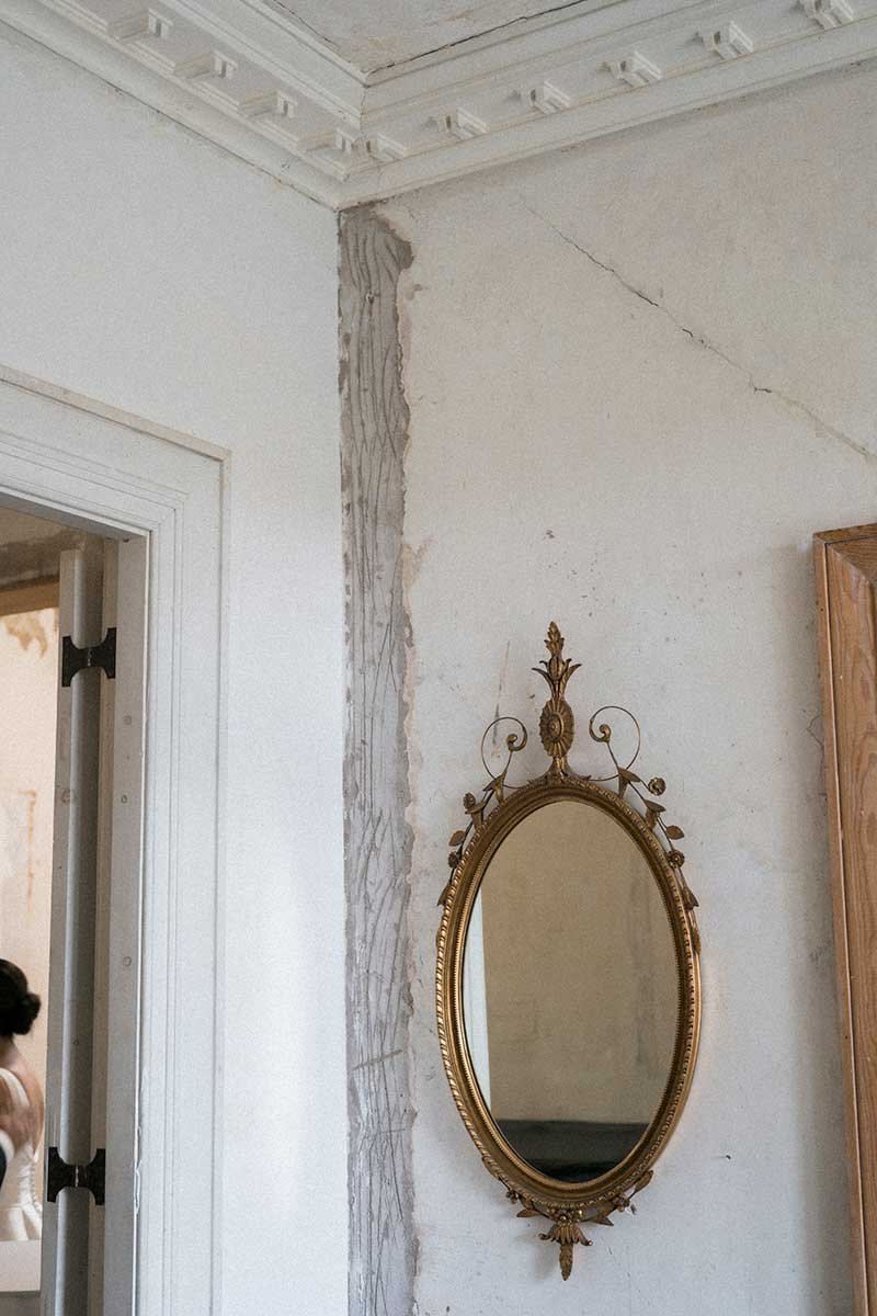  Interior of historic estate wedding venue, crown moulding and ornate mirror. 