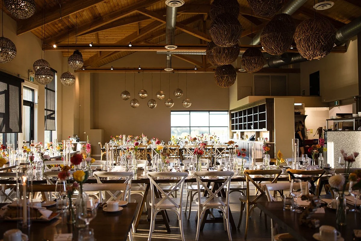 wedding reception with long harvest tables decorated with bud vases at adamo estate winery