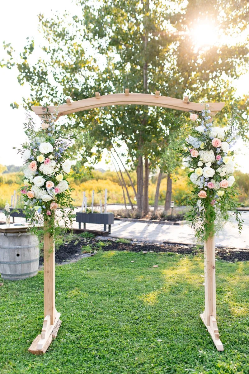 wooden wedding ceremony arbour with floral arrangements on each side