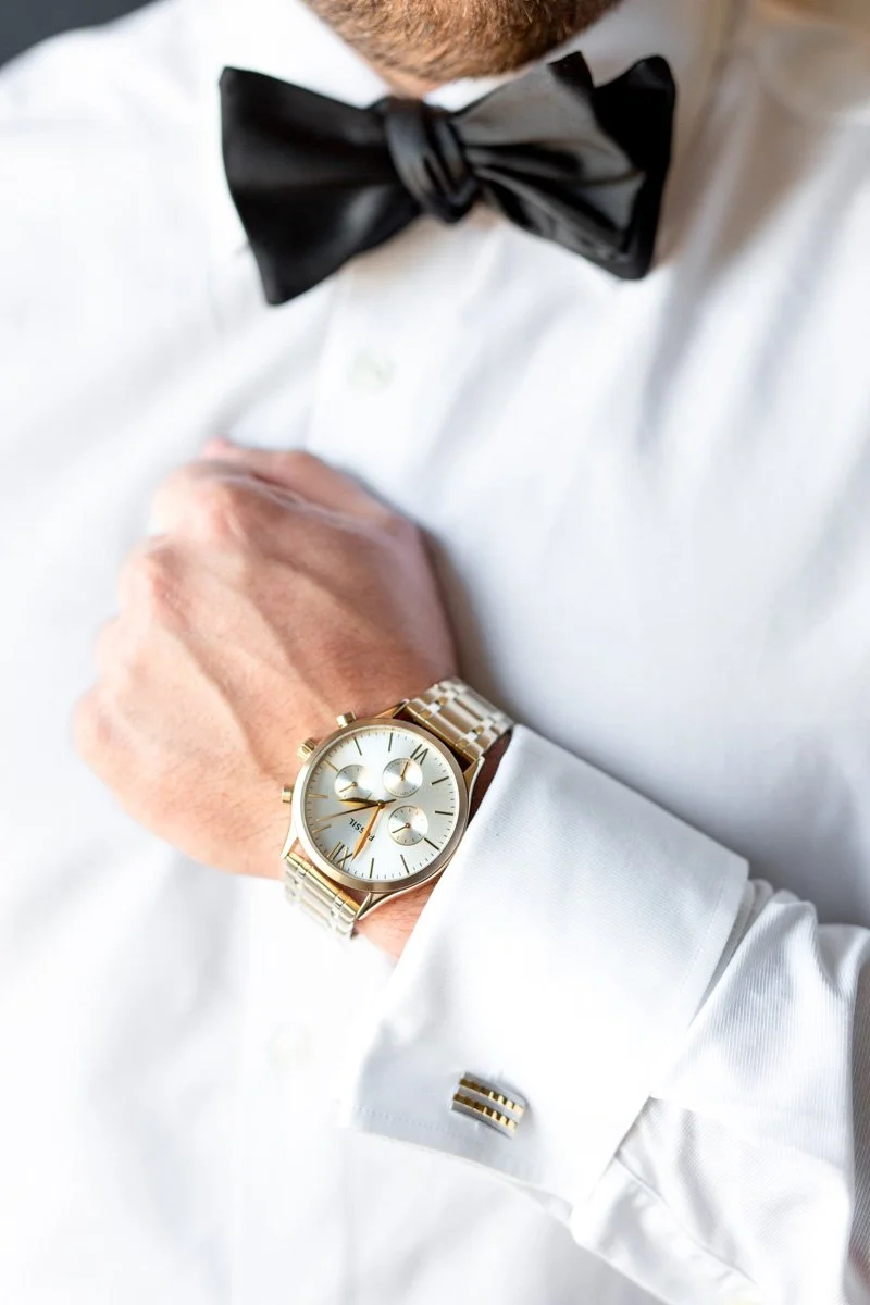 close up of groom's watch with black satin bowtie in view