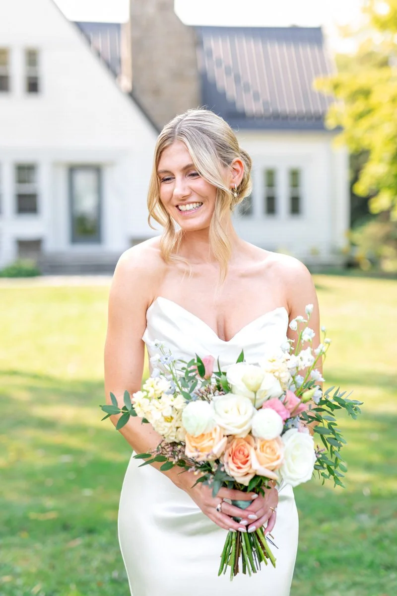 bride with blonde hair and a strapless gown holding a colourful bridal bouquet