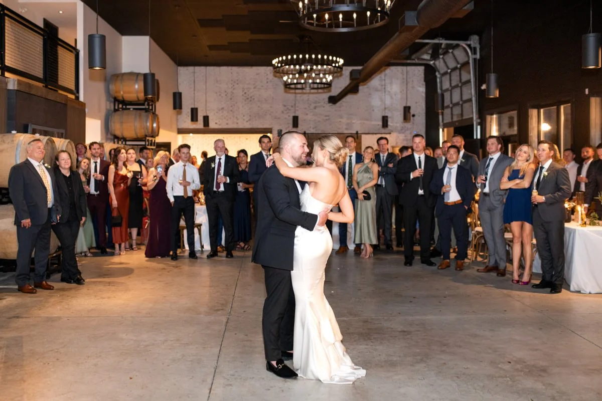 bride and groom sharing their first dance in the middle of their dance floor while guests look on