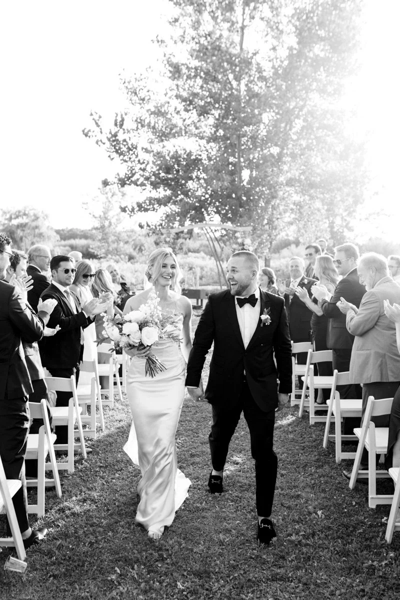 bride and groom walking back up the aisle hand in hand as guests clap