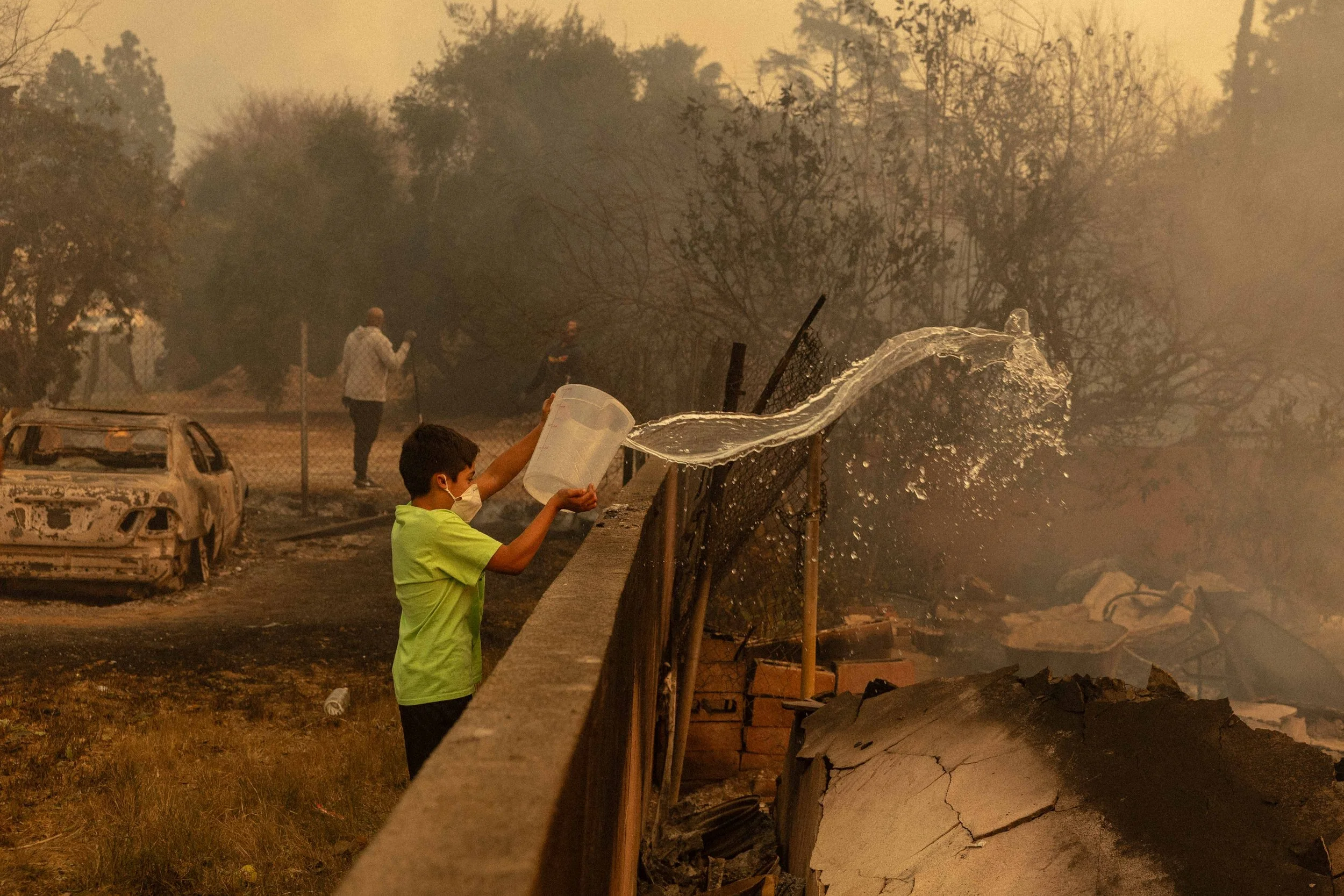 A child throws water onto a smoldering home on the second day of the Eaton fire in Altadena on January 8, 2025.