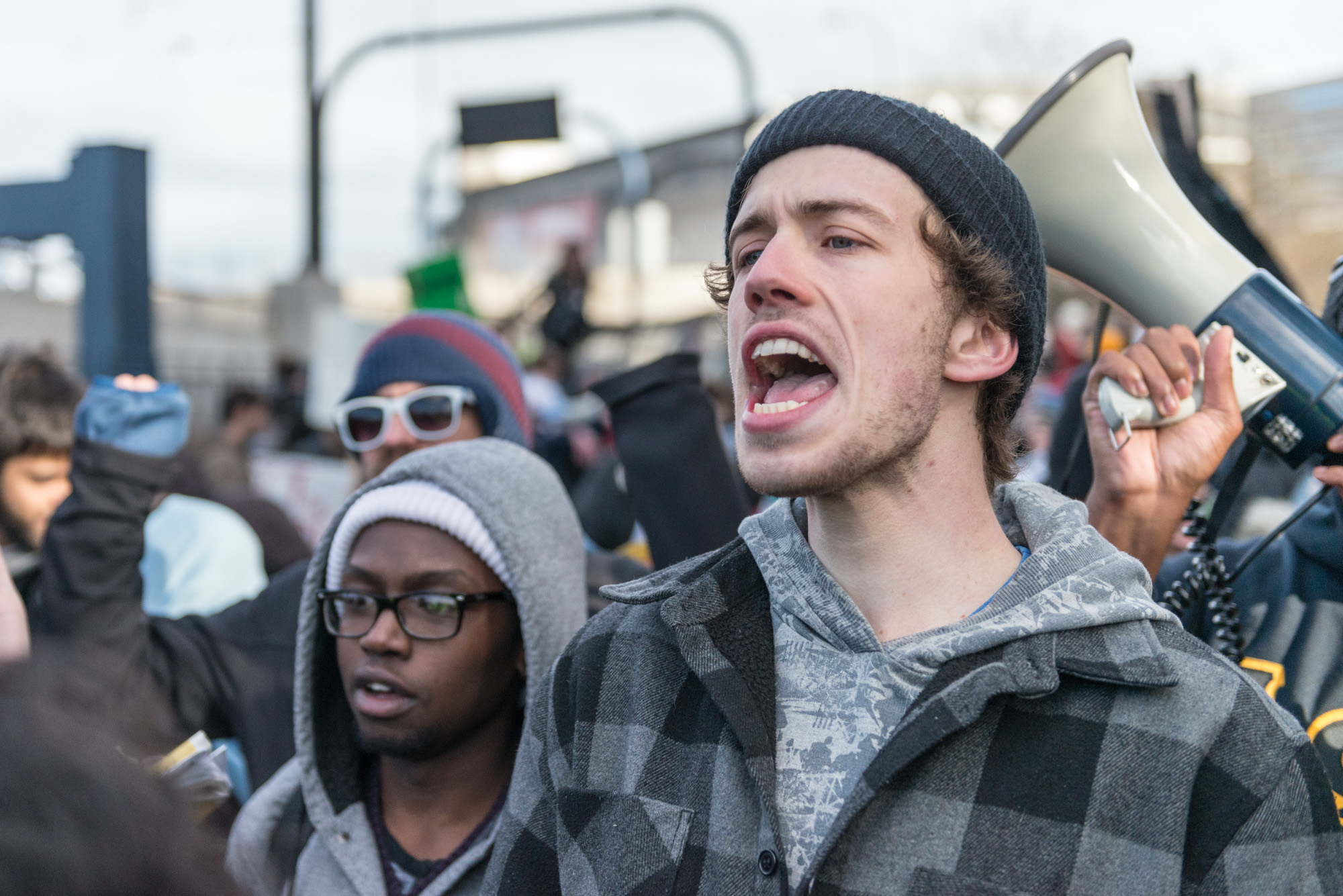 Protester in front of the police fences yelling "Who do you protect, who do you serve!"