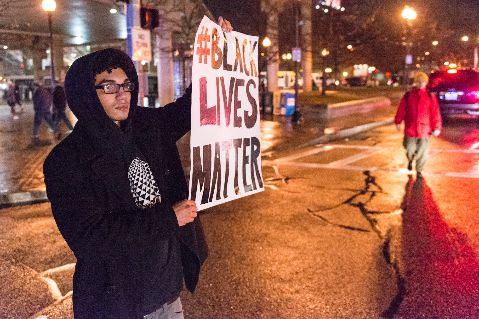Holding a sign for motorists being rerouted past the intersection by police officers