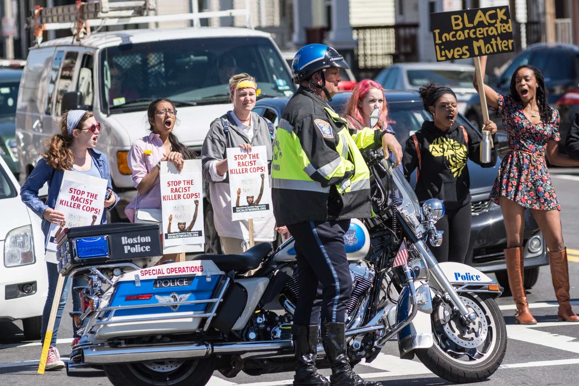 Motorcycle cop in the intersection while protesters block traffic
