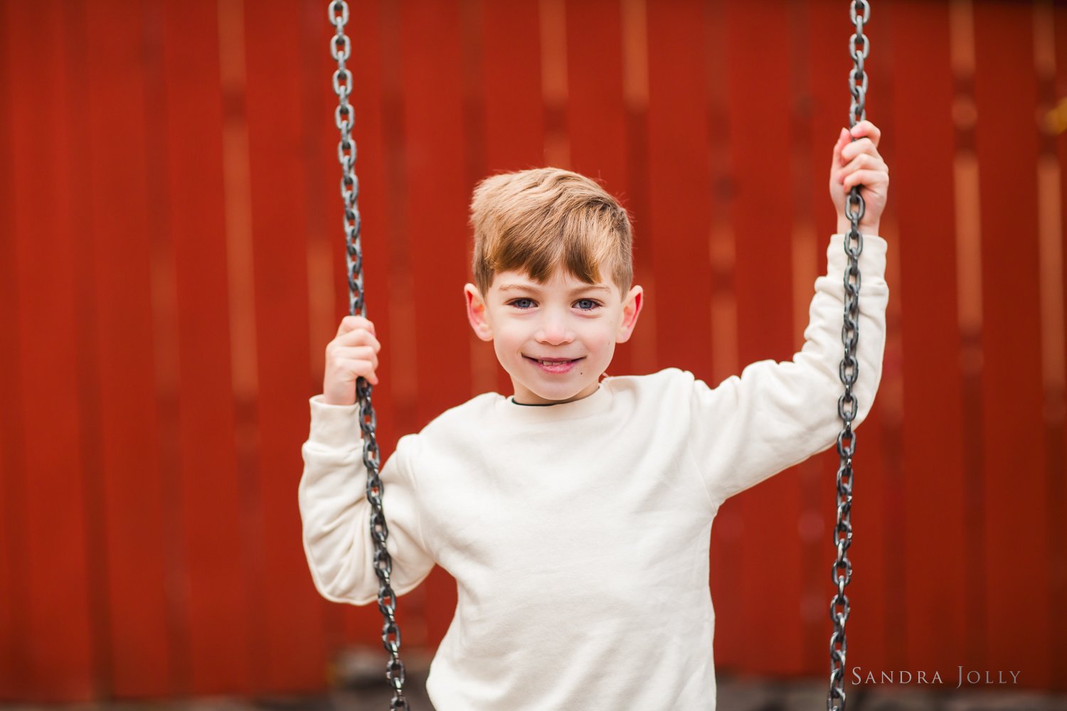 boy-on-a-swing-near-red-fence-in-stockholm.jpg