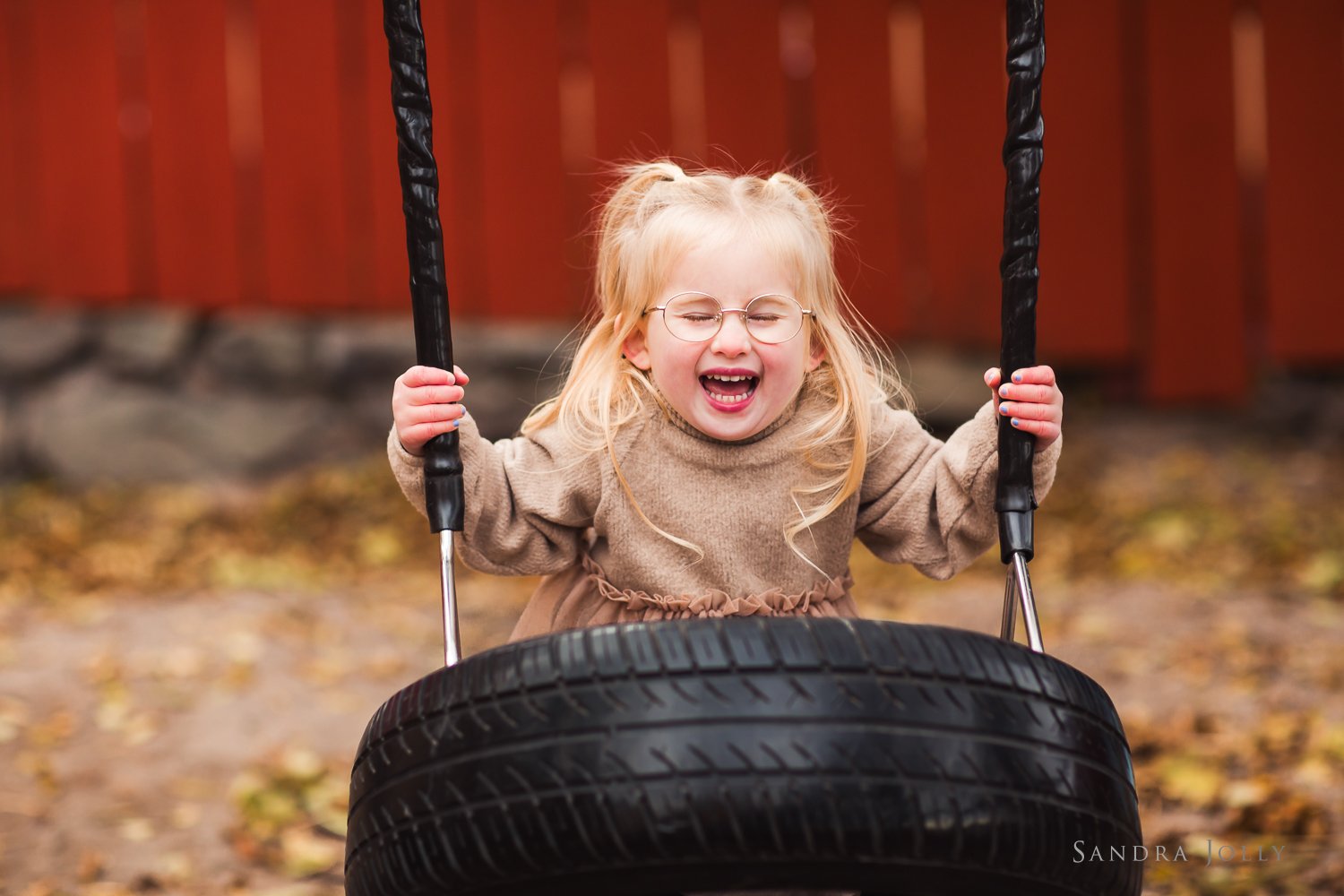 girl-on-a-swing-near-red-fence-in-stockholm.jpg