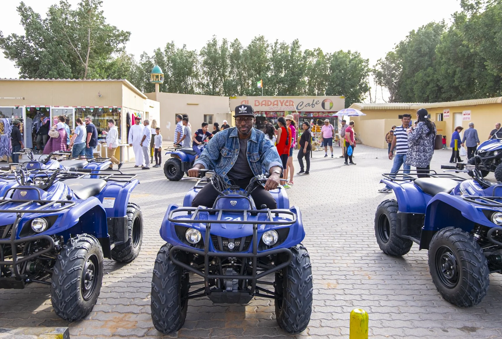 Environmental portrait of NYC photographer Marques Jackson sitting on a blue quad bike at a desert pitstop outside the Lahbab desert in the UAE.