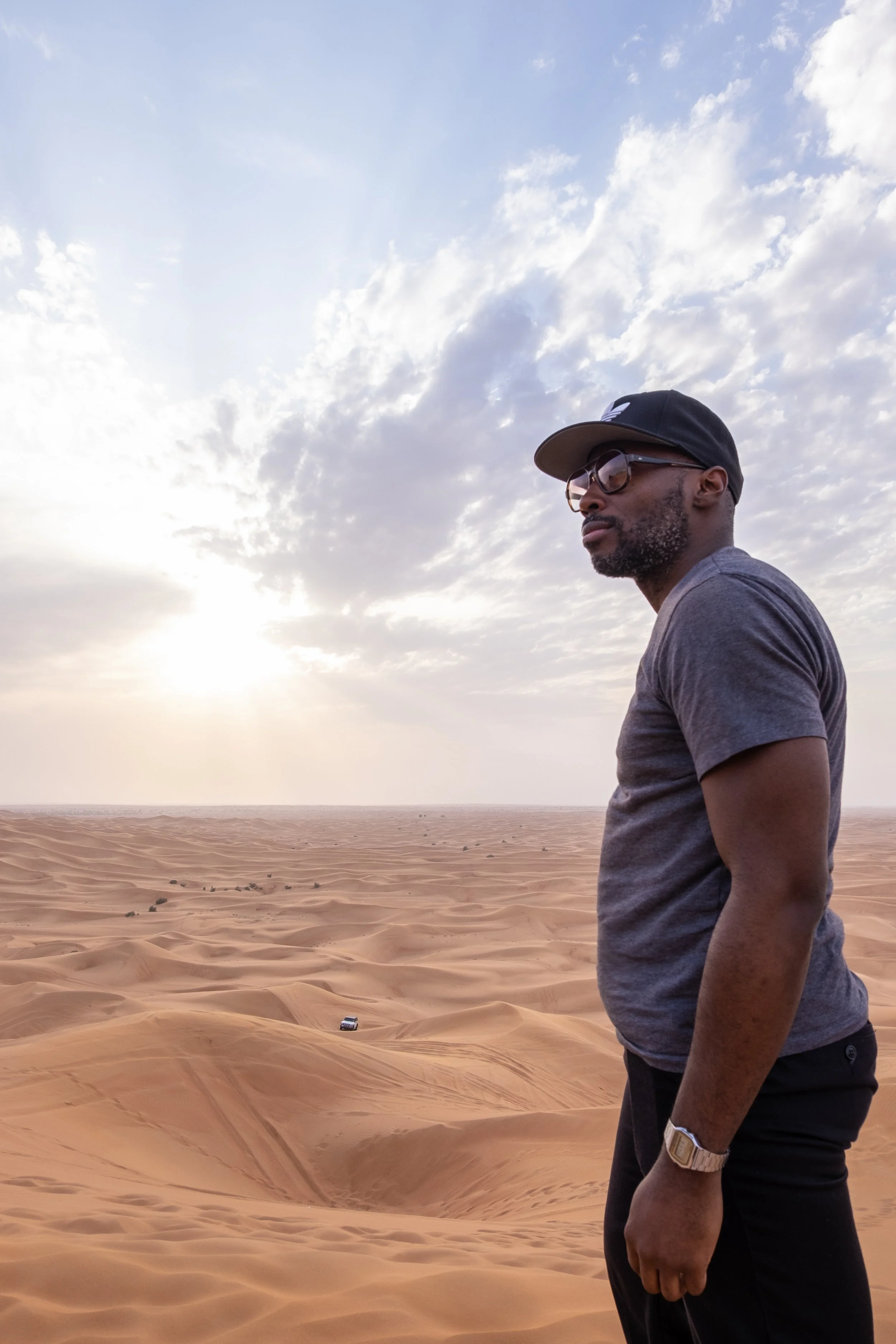 Self-portrait of NYC photographer and visual producer Marques Jackson standing on a sand dune looking over the desert in Lahbab Desert outside Dubai.