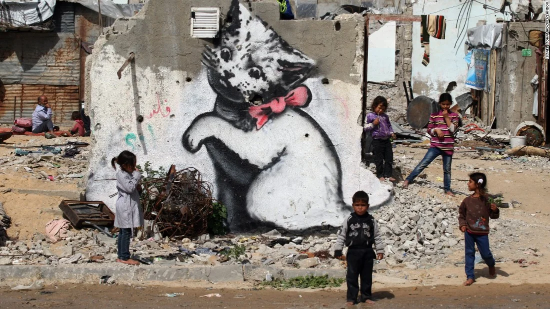 1. Children stand next to a Banksy mural on the remains of a destroyed house in Beit Hanoun, Gaza. The house was destroyed last year during fighting between Israel and Hamas.