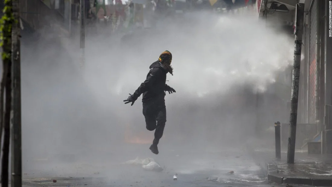 4. A masked protestor runs away as police use water cannons on May Day demonstrators in Istanbul. Clashes erupted between police and protestors who defied a government ban on marching to Taksim Square.