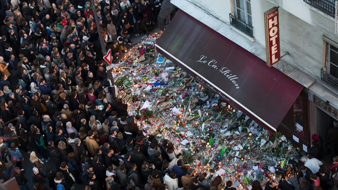 11. A large crowd gathers to lay flowers and candles in front of the Carillon restaurant, one of the establishments in Paris targeted by terrorists in the November 13 attacks.