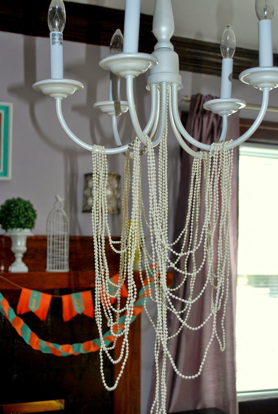 Natasha was searching for many weeks for the perfect chandelier to use as an overhang for the children's table. She discovered the perfect one on Craigslist. She spray painted and decorated it with pearl strands. Super chic!