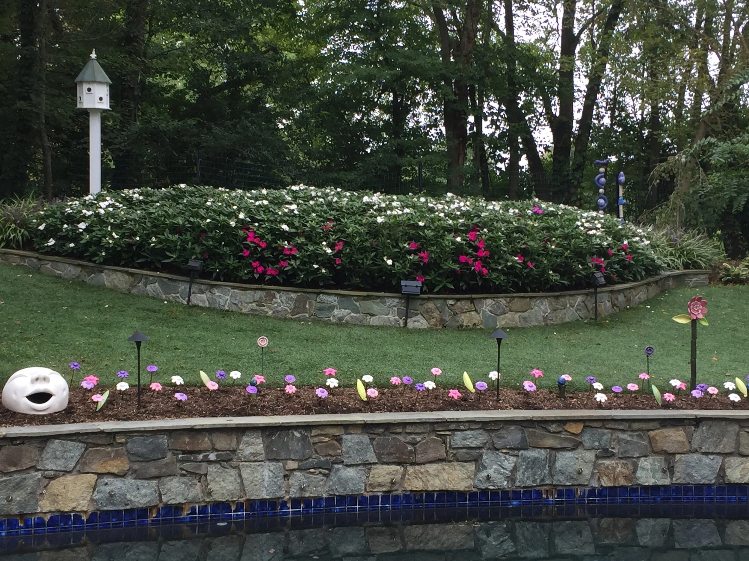 I planted a set of flowers to border the stone wall of this backyard garden this past week. If you look closely, you'll see some of my garden totems in the far right corner of the photo. This garden evolves throughout the seasons with new plantings and garden sculptures (including many of my own)!
