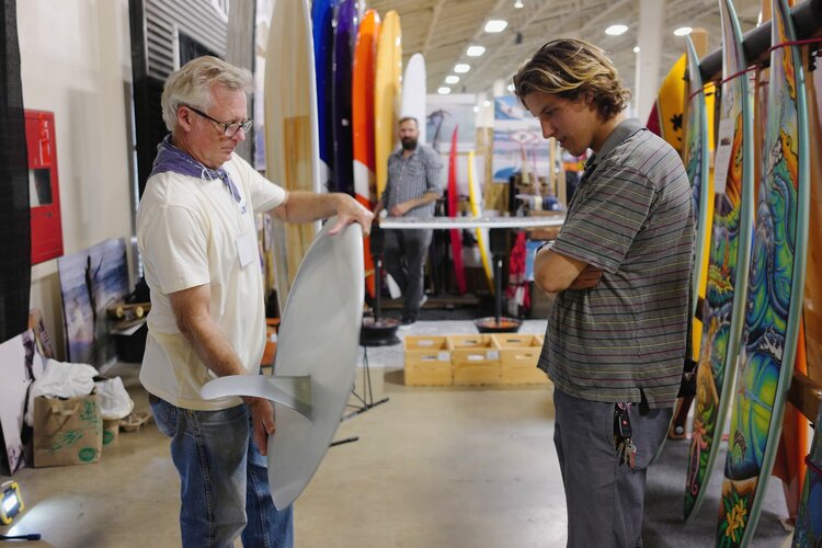 Kirk explaining the subtle nuances of a hull displacement surfboard to an onlooker at The Boardroom Show. Photo by Glenn Sakamoto