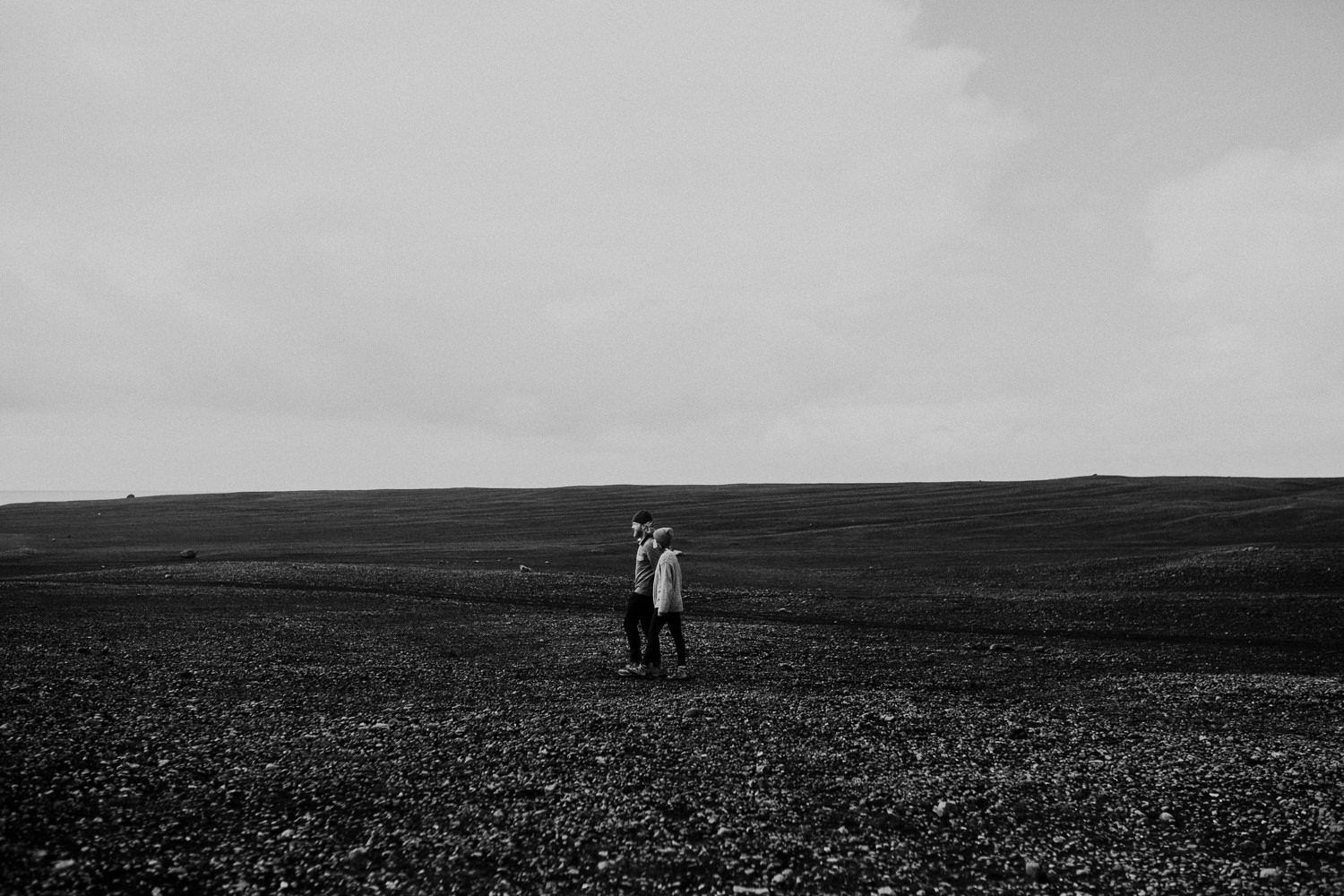 couple walks on black rocks iceland
