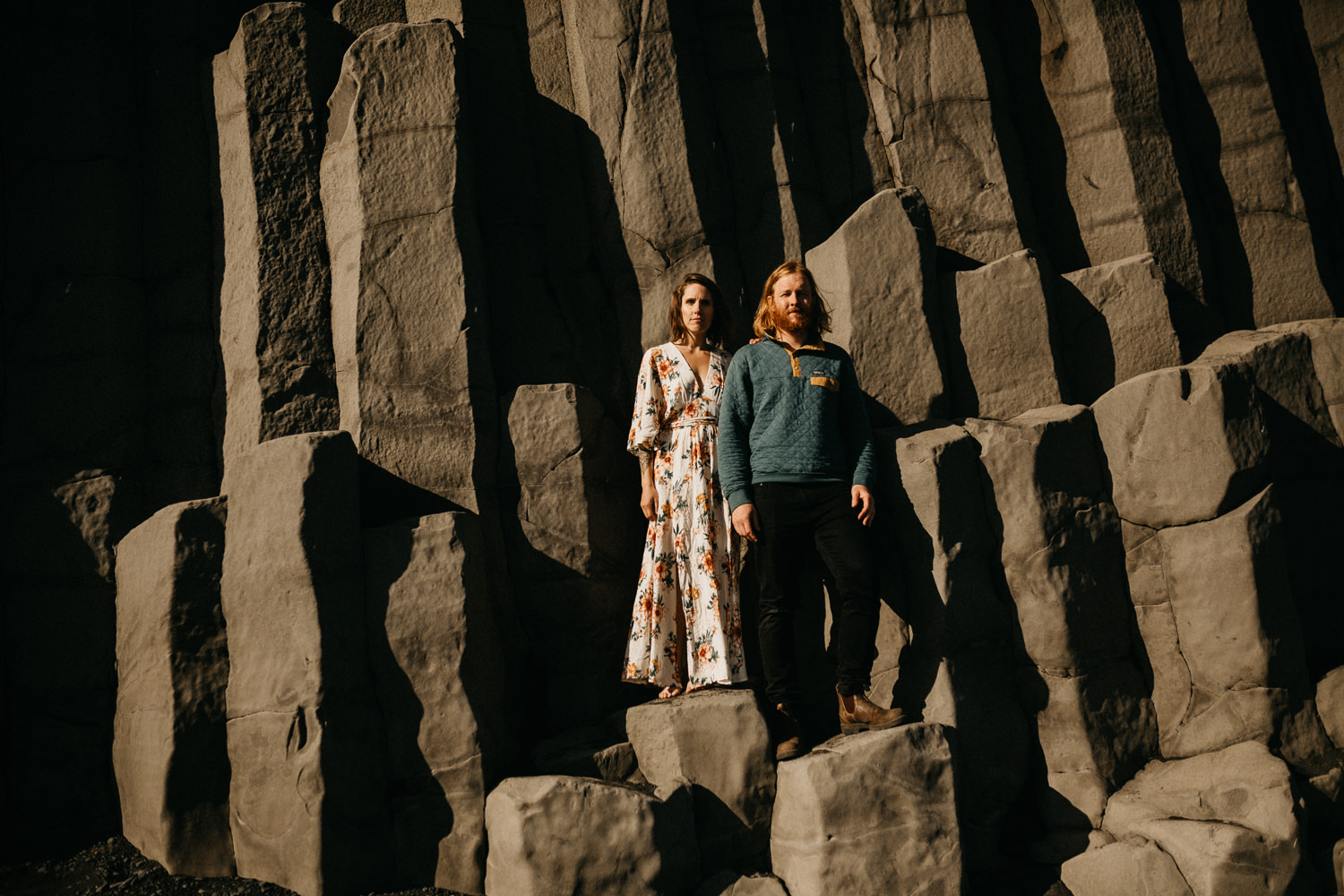 couple stands on rocks vik beach iceland