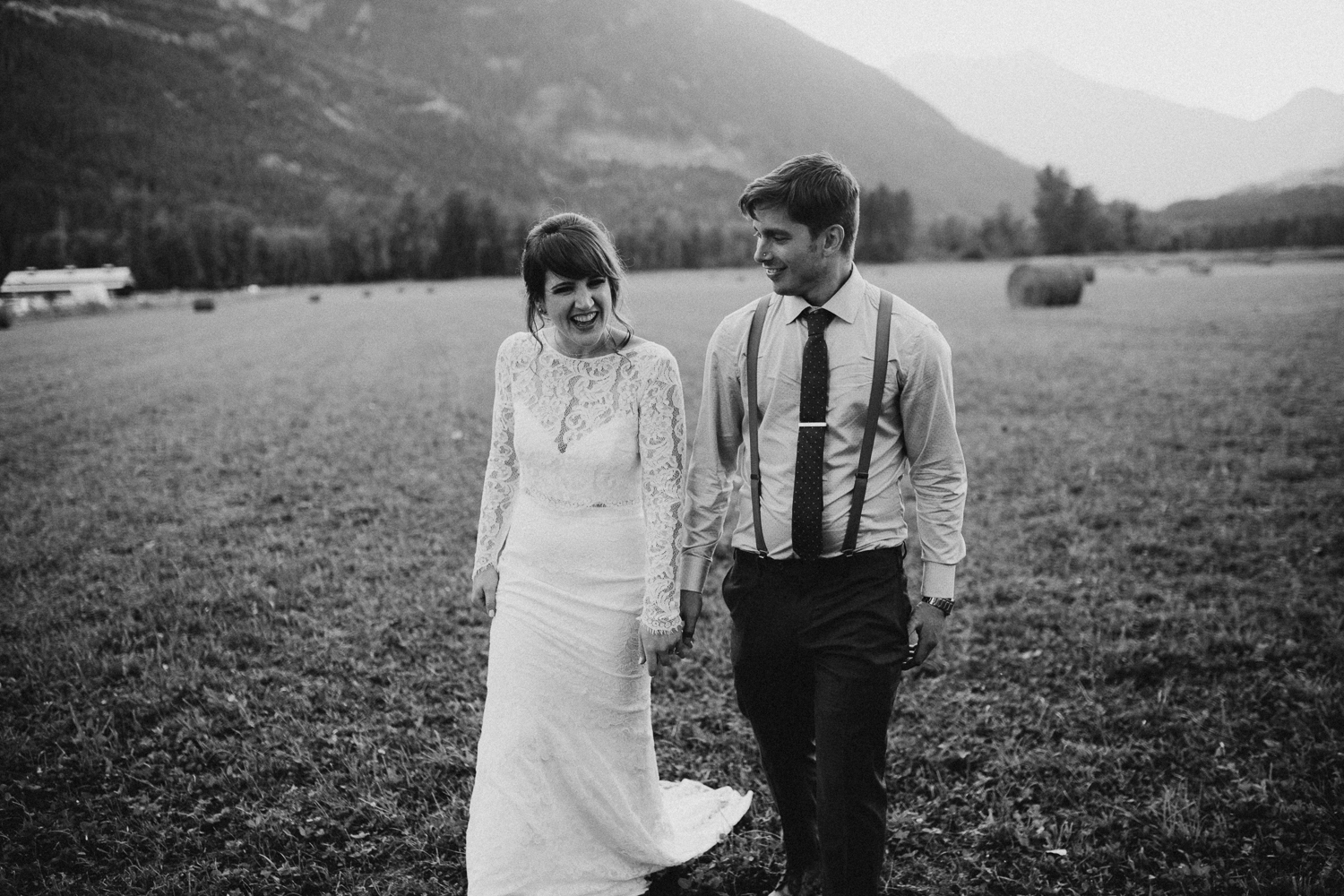 Couple walks hand in hand in field at Pemberton farm wedding